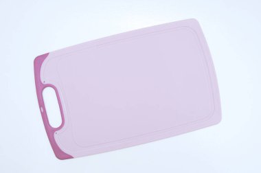 Mutfak pembesi, beyaz bir masada plastik tahta kesiyor..