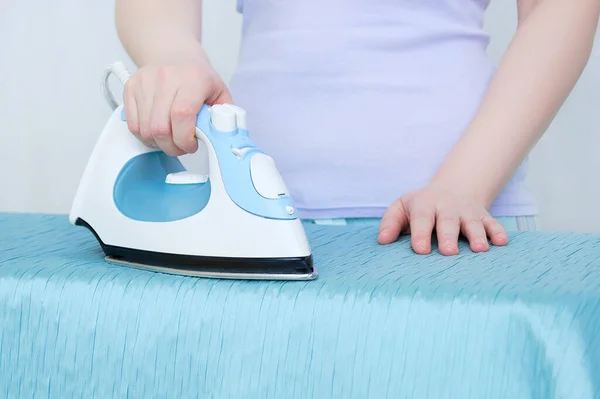 Hands caucasian woman ironing the curtains close-up while standing by an ironing board.