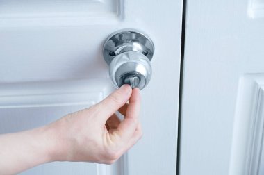 Kapalı el kapı tokmağının mandalını açar..