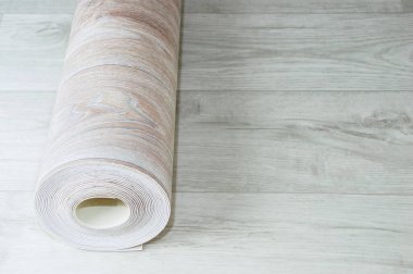 Beyaz ahşap zeminde ahşap desenli bej muşamba rulosu. Ev yenileme ve iyileştirme.