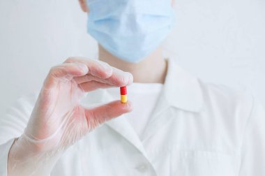 Tablet kapsülü beyaz önlüklü ve eldivenli bir doktorun elinde..