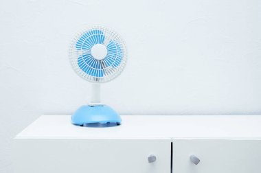 Küçük masaüstü elektrik vantilatörü şifoniyerin üzerindeki odada..
