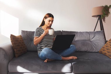 Evde dizüstü bilgisayarda çalışan güzel bir genç kadın..