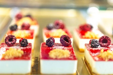 Büyük miktarlarda küçük kekler. Ahududu ve böğürtlenli beyaz pasta..