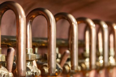 Bakır borular ve kollar. Bira fabrikasındaki cihazın bir parçası. Bira tatmak için musluklar.