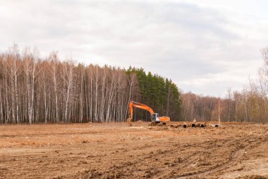 Moskova. - Rusya. 2020 baharında. Kocaman boruları olan bir tarlada buldozer. Büyük bir inşaat projesine hazırlanılıyor