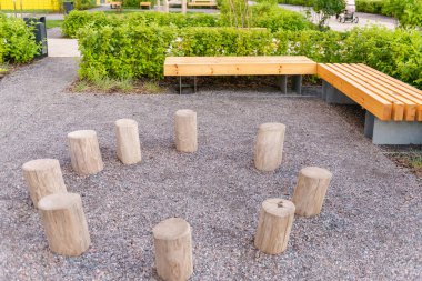 Evin girişinin önündeki peyzaj düzenleme. Banklar ve ağaç kütükleri. Girişin köşesinde güzel çakıllar var..