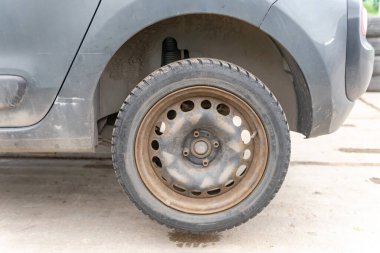 Moskova. - Rusya. 2020 baharında. Pul yapıştırılmış bir diskte araba tekerleği. Paslı bir diskte kış lastiği. Direksiyonu değiştirmeden önce krikodaki araba