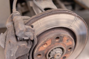 Çok yıpranmış fren diski. Tekerleği çıkardıktan sonra araba fren diski. Değiştirilmesi gereken paslı bir disk.