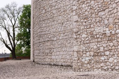 Beyaz taş duvar. Krakow 'un merkezindeki kalelerden birinin duvarı. Taş kaldırım tek bir maddeden yapılmış bir duvara dönüşüyor..