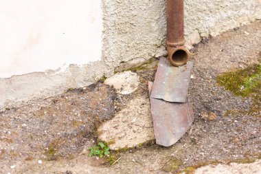 Çatıdaki yağmur suyu drenajı. Sokağa dökülen yağmur suyu için paslı boru ve metal levhalar. Çok ilkel bir rögar borusu..