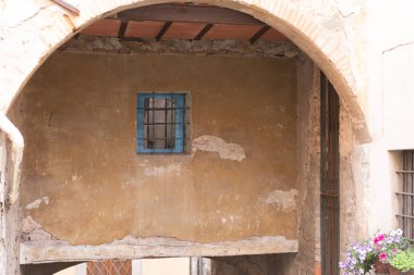 Kemerin altındaki parmaklıklı pencere. Barga 'daki evlerden birinin altında bir kemer. Ortaçağ şehrinin ayrıntıları.