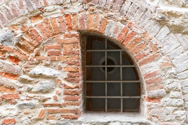 They laid a semicircular window with a brick. A walled-up window that\'s hundreds of years old. Masonry of old bricks.