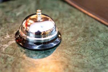 Otel resepsiyonunu arayın. Masanın üzerinde fotoğrafçıyı yansıtan parlak mekanik bir zil..
