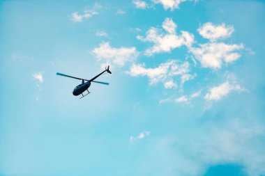 Gökyüzüne karşı bir helikopter. Küçük bir helikopter öne doğru uçar. Sadece iki bıçakla hareket eden bir helikopter görüntüsü..
