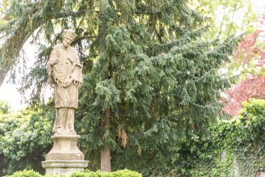 Brno Kalesi bahçesindeki anıt. Bahar ağaçlarının arkasındaki bir adam için taş bir anıt..
