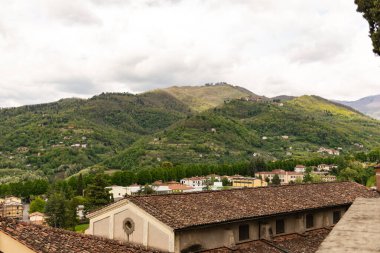 Eski kiremitli çatı. İtalya 'nın dağlarındaki Toskana' nın ortaçağ şehri Barga 'nın güzel çatıları. Şehrin dışındaki güzel dağlar.