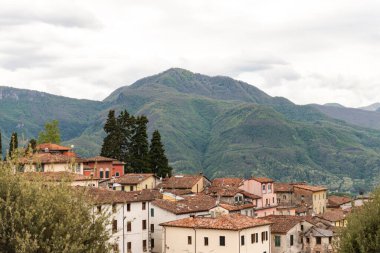 Eski kiremitli çatı. İtalya 'nın dağlarındaki Toskana' nın ortaçağ şehri Barga 'nın güzel çatıları. Şehrin dışındaki güzel dağlar. Eski evler çıkıntıdır..