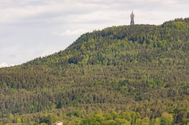 Dağdaki TV kulesi. Avusturya dağlarında yeşil bahar ormanı. En yüksek tepede güzel tasarlanmış bir kule var..