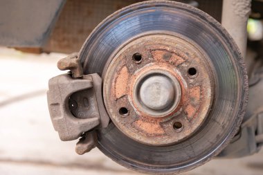 Eski araba fren diski. Arabanın frenleri düzenli bakım gerektiriyor. Tekerleği değiştirirken fren diski ve pedlere çok yakın çekim.