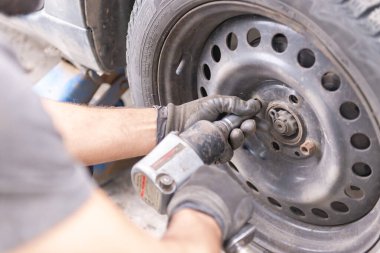 Moskova. - Rusya. 2020 yazında. Sezondan önce tekerlek değiştirme. Lastik servisi serviste. Usta tekerlek tamiri yapmadan önce vidaları söküyor. Sahne fotoğrafı değil..