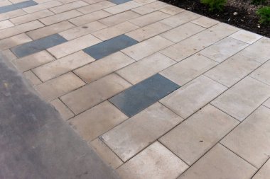 Bahçede kiremit ve asfalt kombinasyonu. Farklı malzemelerden yapılmış iki yol avluda kesişiyor..