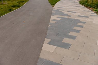 Bahçede kiremit ve asfalt kombinasyonu. Farklı malzemelerden yapılmış iki yol avluda kesişiyor..