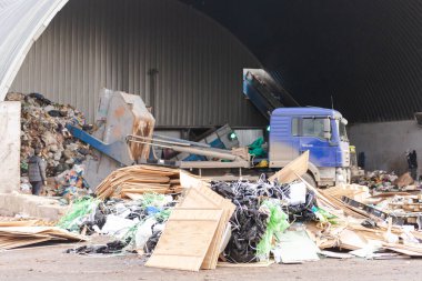 Çöp kamyonunun önünde bir inşaat enkazı yığını. Çöp kamyonlu bir çöp fabrikasında hangar..