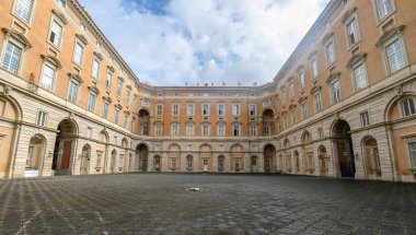 Caserta Kraliyet Sarayı veya Reggia di Caserta cephesi yeşil bahçe ve mavi gökyüzü, İtalya