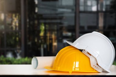 İnşaat evi ve bina. Tamir işleri. Beyaz masaya miğfer ve bina çizimleri.