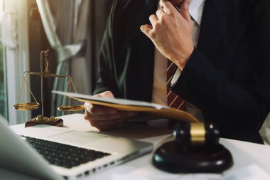 Adalet ve hukuk kavramı. Bir mahkeme salonunda tokmakla çalışan bir erkek yargıç, bilgisayar ve kenetlenme klavyesi, gözlük, masa başında