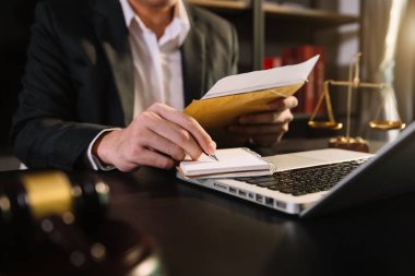 Adalet ve hukuk kavramı. Tahta masadaki akıllı telefon, dizüstü bilgisayar ve dijital tablet bilgisayarla çalışan tokmak mahkemesindeki erkek yargıç.