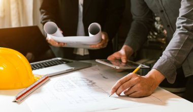 Çalışma ve tablet hakkında konuşan iki meslektaş, ofisteki inşaat alanında mimari projeyle ilgili bilgisayarı açtılar.