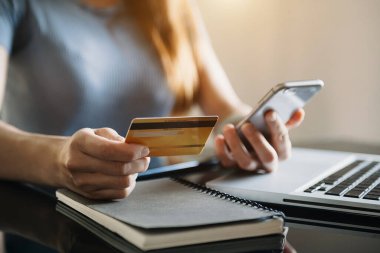 Akıllı telefon, tablet ödemeleri ve kredi kartı online alışveriş, omni kanal, Sun Ligh 'deki ofiste dijital tablet kenetleme klavyesi bilgisayarı kullanan iş kadını.