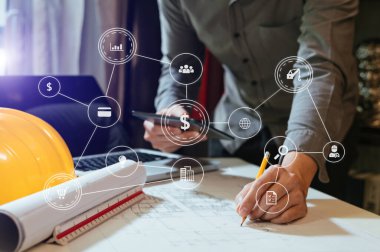 İşadamı el işi ve dizüstü bilgisayarla ofisteki inşaat alanında mimari proje üzerinde çalışıyor.