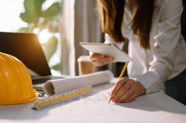 İşadamı el işi ve dizüstü bilgisayarla ofisteki inşaat alanında mimari proje üzerinde çalışıyor.