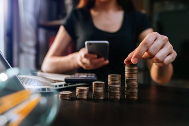 Bütçe kavramını hesaplamak için cep telefonu ve hesap makinesi kullanan bir muhasebeci. 