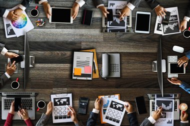 Modern ofiste bilgisayar, akıllı telefon, tablet, kahve ve belgeyle bir araya gelen çok ırklı iş adamlarının en iyi görüntüsü..