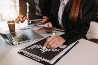 Sosyal ağ diyagramlı dizüstü bilgisayar ve tablet kullanan iş adamı ve masadaki verileri kavram olarak tartışan iki meslektaşı