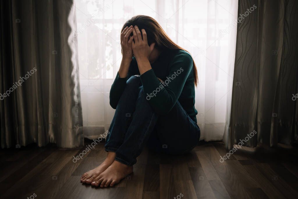  woman in Depression at home at window with curtains, melancholy and hopeless mood 
