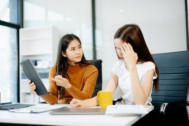Asyalı kadın, sıkıntılı iş arkadaşını ofisinde rahatlatıyor. Profesyonel ortamlarda işyeri stresi, tükenme, empati ve duygusal destek kavramı.