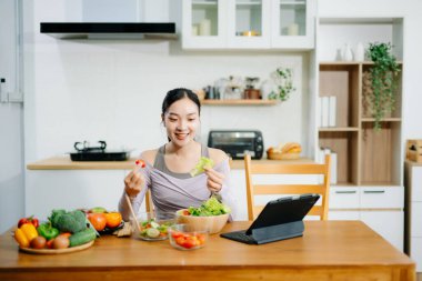 Mutfakta genç bir kadın ve evde sağlıklı yemek tarifi ya da günlük diyet yazıyor. Aktif sağlıklı yaşam tarzı, temiz yeme konsepti