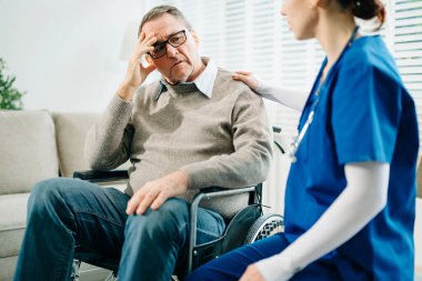 Yaşlı bir erkeğin omzuna dokunan kadın eli, hastanedeki yaşlı kavramının icabına bakar.