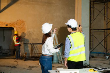 Müteahhit ve mimar plan, tablet, dizüstü bilgisayar ve büyük bir proje üzerinde çalışmaktan bahsediyorlar. İnşaat sürecinin içinde bina. takım çalışması 