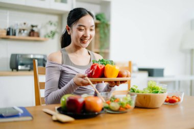Mutfakta genç bir kadın ve evde sağlıklı yemek tarifi ya da günlük diyet yazıyor. Aktif sağlıklı yaşam tarzı, temiz yeme konsepti