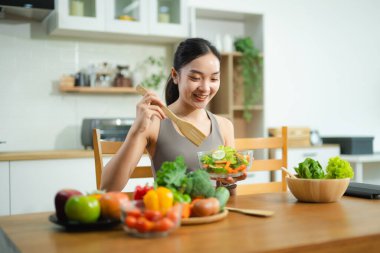 Gülümseyen Asyalı kadın ev mutfağında taze sebze salatası hazırlıyor. Sağlıklı yaşam tarzı, temiz yemek, sağIık ve zindelik gıda hazırlık konsepti..