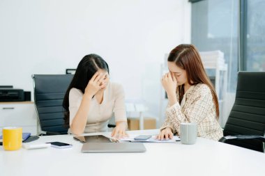 Asyalı kadın, sıkıntılı iş arkadaşını ofisinde rahatlatıyor. Profesyonel ortamlarda işyeri stresi, tükenme, empati ve duygusal destek kavramı.