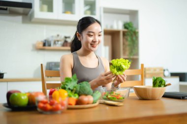 Gülümseyen Asyalı kadın ev mutfağında taze sebze salatası hazırlıyor. Sağlıklı yaşam tarzı, temiz yemek, sağIık ve zindelik gıda hazırlık konsepti..