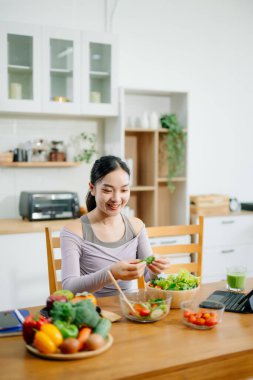 Mutfakta genç bir kadın ve evde sağlıklı yemek tarifi ya da günlük diyet yazıyor. Aktif sağlıklı yaşam tarzı, temiz yeme konsepti