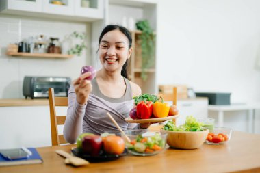 Genç bayan taze meyve, sebze ve besleyici malzemelerle sağlıklı tarifler hazırlıyor. Temiz ve sağlıklı bir yaşam tarzı için mükemmel.